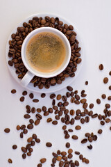 Cup of black coffee and saucer with coffee beans on white background.	
