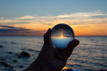 Beach and sea reflected in a ball in a human hand
