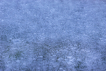 Abstract background of bubbles of air under layer ice in clear water lake