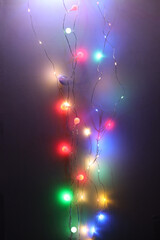 Soft focus blur Christmas color garland lights on dark wall background.