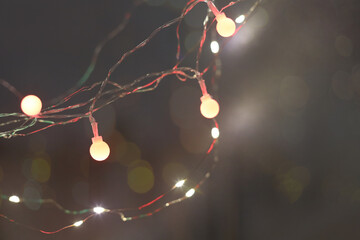 Soft focus smoke blur Christmas color garland lights on dark wall background.