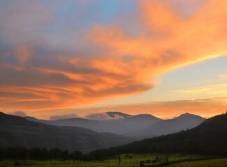 Naklejka na ściany i meble Cloudy sunset over the mountains
