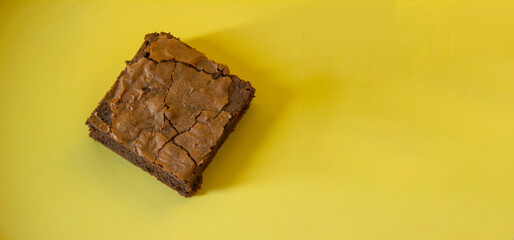 Panoramic picture of a dark chocolate brownie on yellow dish.