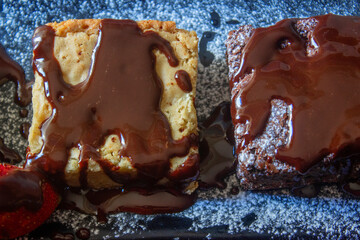 Tree pieces of black and white brownies with liquid chocolate
