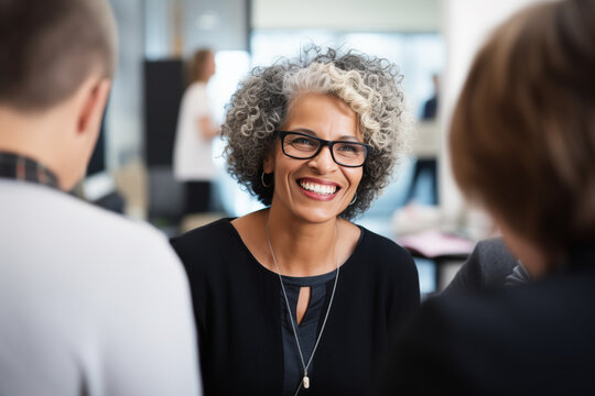 Confident senior business woman talking at workplace with colleagues. 