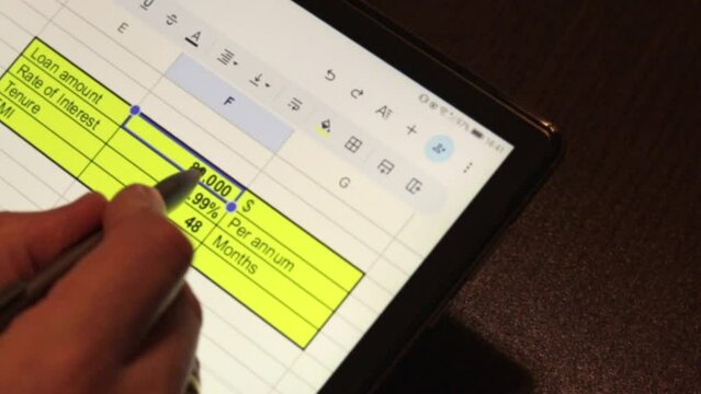 Business person working on wooden table Indoors, using tablet and stylos, looking on the screen showing bank loan amortization table. Finance