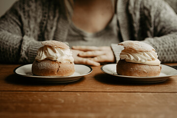 Concept of picking pastry to eat. Focus on traditional Swedish pastry, semla, on the plates at...