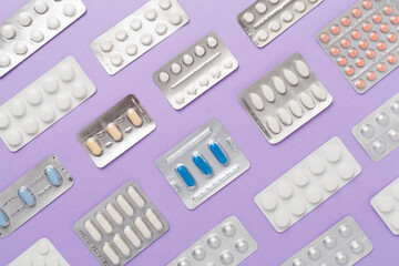 Pills in blister packaging on color background, top view