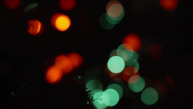 Colorful bokeh holiday lights flickering in the dark. Abstract Christmas background. Slow motion. 
