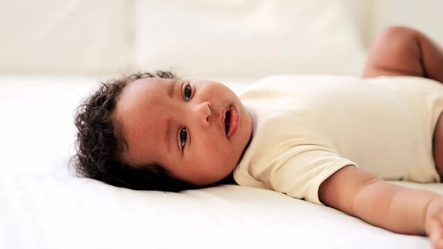 sneezing black african american baby on a white bed, sick snotty baby