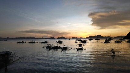 Beautiful beach scene featuring a stunning sunrise illuminating a fleet of boats.