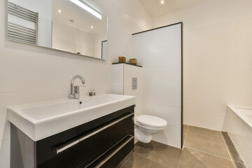 a modern bathroom with black and white fixtures on the wall, sink and toilet in the photo is taken...