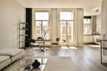 Fototapeta premium a living room with wood flooring and white walls, including two couches and a coffee table in the corner