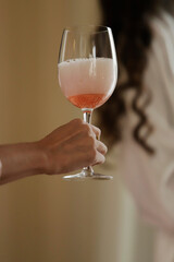 woman's hand holding glass of pink champage