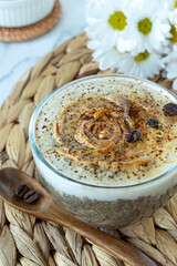 Coffee chia seed pudding with peanut butter in glass and wooden spoon on rustic table. Close-up, vertical shot. Selective focus. Sweet and creamy plant-based breakfast drink.