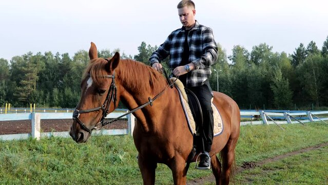 A young man on horseback. Farmer on horseback. A man riding a horse. Outdoor stable