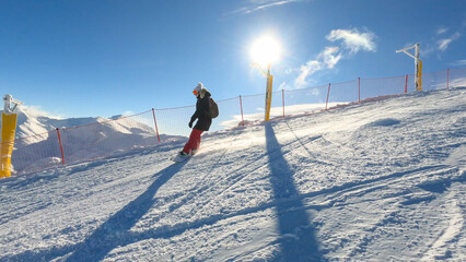 LENS FLARE: Snowboarder carving down the picturesque slope at snowy ski resort