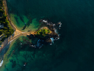 Aerial view of tranquil coastal vista with lush greenery and azure waters, ideal for travel brochures and postcards promoting serene vacations and tropical getaways. Parrot rock island in Sri Lanka.