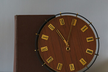 An old book and old clock with Roman numerals on the dial. Antique times, ancient laws, auction...
