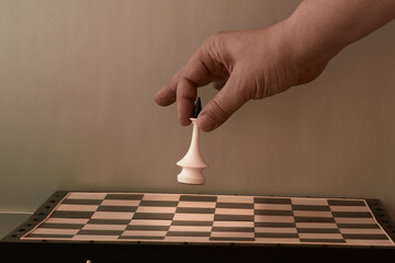 The beginning of the game, the start of political election. A person's hand lowers a chess king onto the chessboard and the light falls not on the figure.