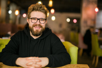 Close up portrait of young handsome freelance man wearing stylish eyeglasses on cafe. Happy...