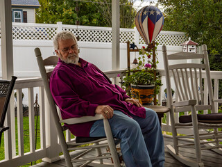 A Senior Aged Male Sleeping in a Rocking Chair, on a Deck, Enjoying His Retirement on a Autumn Day