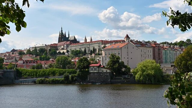 Prague,Czech Republic, August 4,2023. Postcard image of the city: the castle on the hill is framed by the trees and the river. Beautiful summer day.