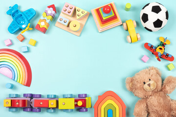 Baby kids toy frame background. Teddy bear, colorful wooden educational, sensory, sorting and stacking toys for children on light blue background. Top view, flat lay