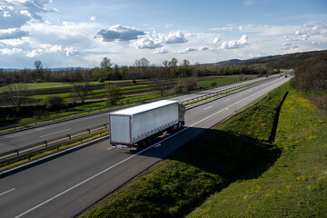 Transportation truck passing by on a country highway under a beautiful sky. Business Transportation And Trucking Industry. White trucks driving on the highway.