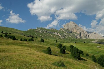 Scenic landscape of a mountain surrounded by lush green vegetation and a blue sky.