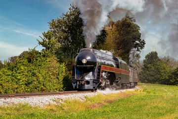 A View of a Steam Passenger Train Approaching Around a Curve, Traveling Thru Rural America, Blowing Smoke on a Summer Day