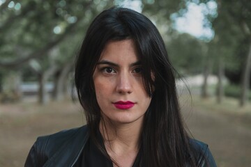 Young woman wearing a black jacket and pink lipstick while looking into the camera