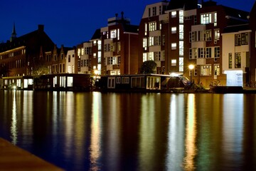 Fototapeta na wymiar Scenic view of the river and city buildings illuminated at night. Leiden, the Netherlands