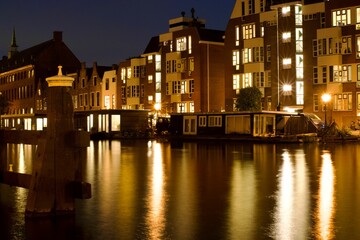 Obraz premium Scenic view of the river and city buildings illuminated at night. Leiden, the Netherlands
