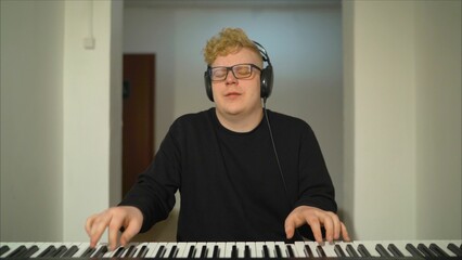 A composer with headphones playing the digital piano. Musician playing synthesizer