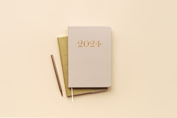Year 2024 diary planner on a beige background, top view - Powered by Adobe