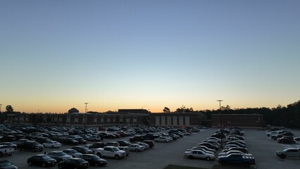 Busy outdoor parking lot with a variety of vehicles parked in front of a school © Wirestock