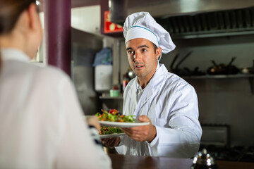 Service process in cafe - chef serves ready meals to visitors of restaurant