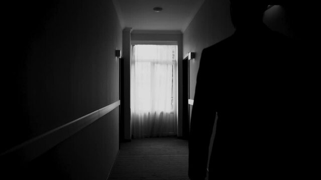 a dark black corridor and a room along which a man in a jacket and a classic suit walks, a businessman and a gentleman go to a business meeting in the office