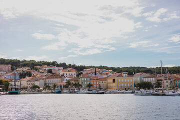 Fototapeta na wymiar View of houses rising above the mali losinj bay across the marina, on a sunny autumn day. Different boats in the foreground.