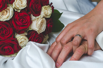 hands of married couple with rings and roses