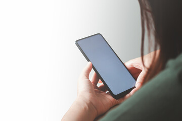 Close up of beautiful Asian woman hand holding smartphone mockup of blank screen, shot from rear view. Isolated on white background.