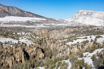 Snow-covered winter landscape in northwest Wyoming wilderness of canyons, mountains and forest with a blue cloudless sky.