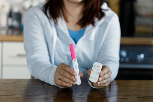 Woman holding positive pregnancy test and positive COVID test. Pregnant woman being sick cannot use medicine.
