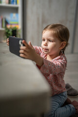 One girl toddler child play video game on mobile phone smartphone