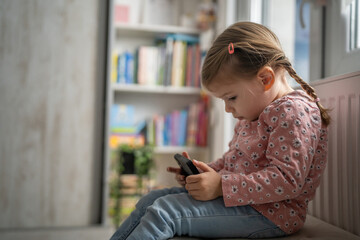 One girl toddler child play video game on mobile phone smartphone