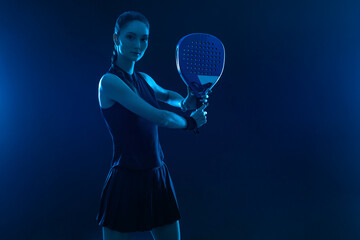 Padel tennis player with racket on tournament. Girl athlete with paddle racket on court with neon...