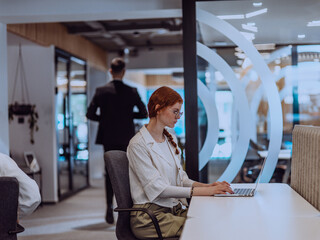 A young businesswoman with orange hair sitting confidently, fully engaged in her work on the...
