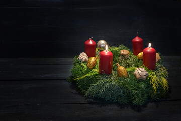 Light in the dark on second advent, natural green wreath with red candles, two are burning, Christmas decoration and cookies, dark wooden background, copy space - Powered by Adobe