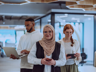 A diverse group of young businessmen, including a Muslim woman wearing a hijab, an orange-haired...